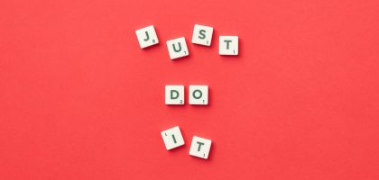 Motivational phrase 'Just Do It' spelled with Scrabble letters on a red background.