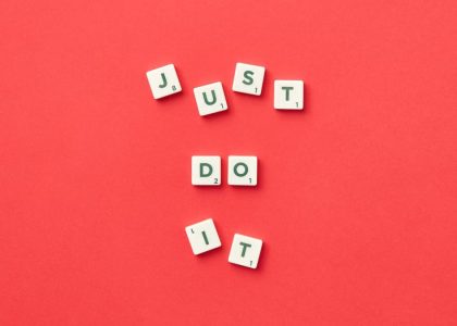 Motivational phrase 'Just Do It' spelled with Scrabble letters on a red background.