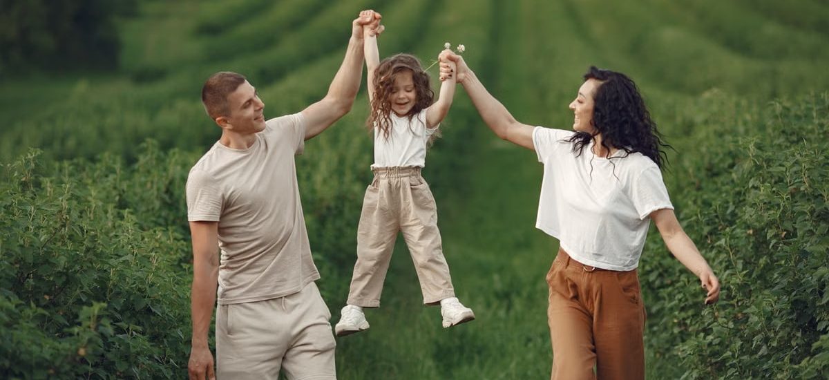 Joyful family moment in a green field during summer, capturing love and playfulness.